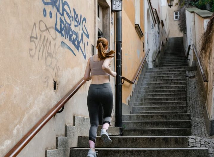 Back view of a female runner exercising on outdoor stairs in an urban setting.