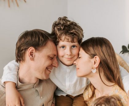 A joyful family moment with parents and their son embracing indoors.
